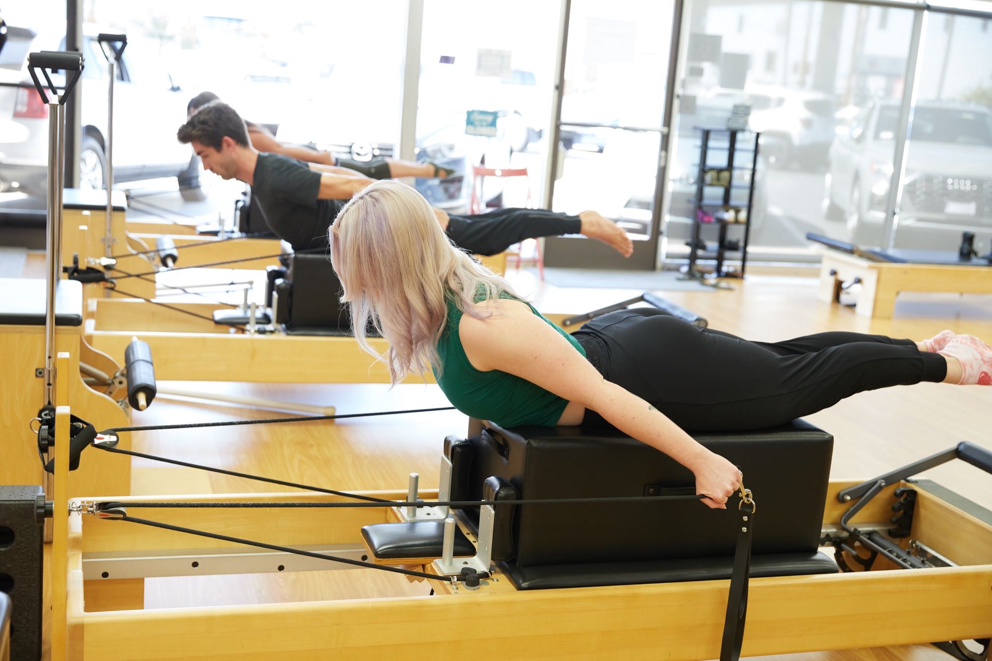 Two clients training side by side on reformers in the window light at Love Pilates